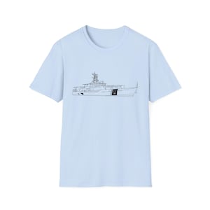 May include: Light blue t-shirt featuring a black line drawing of a ship. The ship design includes detailed elements such as the superstructure, radar, and hull. The shirt is a solid color, with a crew neck and short sleeves.