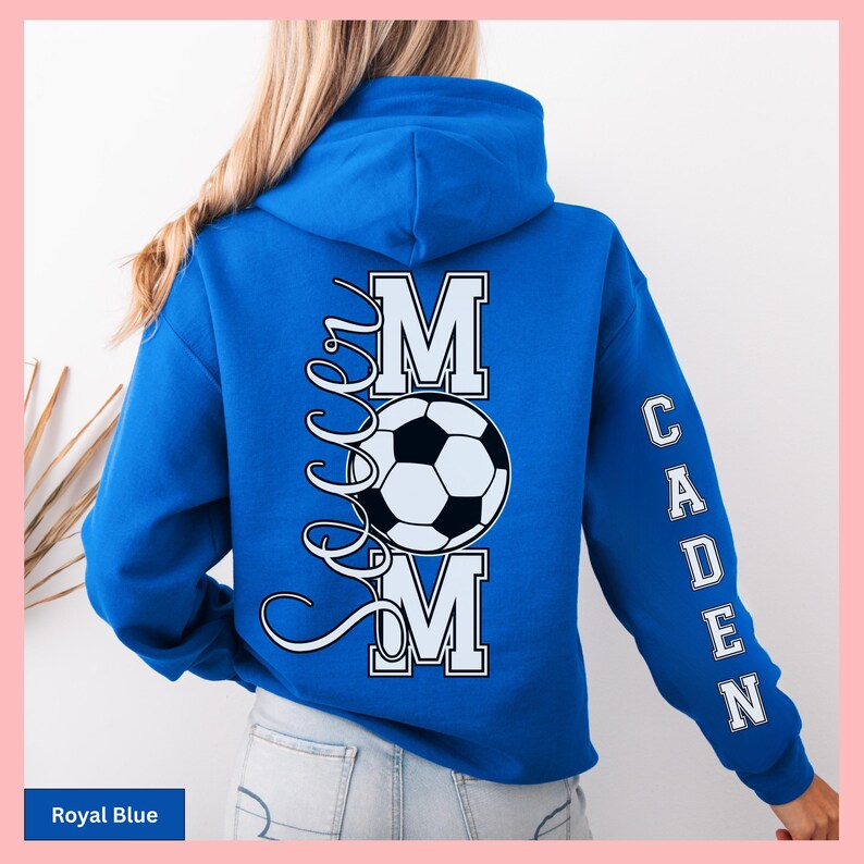 May include: Royal blue hoodie with the text "Soccer Mom" and a soccer ball graphic on the back. The name "Caden" is printed vertically on the right sleeve. The hoodie is a solid royal blue color.