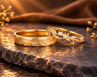 May include: Two gold rings featuring intricate leaf and vine engravings. One ring is a solid band with etched foliage, while the other is a delicate, open-work band adorned with small, clear, round-cut stones set within the leaf-shaped metal design.