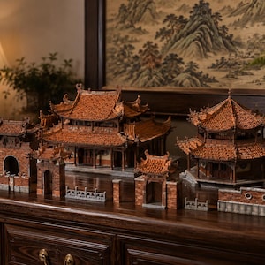 Può includere: Una collezione di modelli architettonici in miniatura con design di edifici tradizionali dell'Asia orientale, caratterizzati da complesse strutture in legno marrone e tetti in tegole arancioni, inclusi portali, un salone principale e un padiglione.