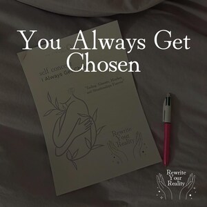 May include: A book with the text "You Always Get Chosen" and "Rewrite Your Reality" is displayed. The book has a line drawing of a person with leaves. A pink pen rests on the surface.