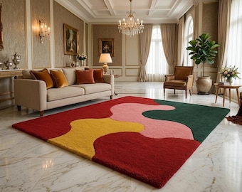 May include: A rectangular area rug featuring a bold, abstract pattern with large, organic shapes in solid blocks of deep red, mustard yellow, soft pink, and dark forest green. The rug has a thick, textured pile and sits on a polished marble floor.