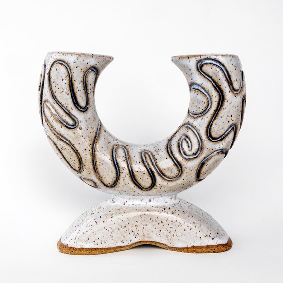 A hand-carved ceramic sculptural vase where the carving IS the art — surface texture and abstract relief make it look more gallery than garden center.