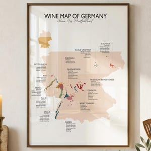 Pode incluir: Um poster de parede emoldurado intitulado WINE MAP OF GERMANY Weine Aus Deutschland, apresentando um mapa bege claro da Alemanha com regiões coloridas e texto preto listando vários tipos de vinho, numa moldura fina castanho-escura.