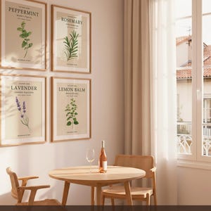 May include: Four framed botanical prints featuring Peppermint, Rosemary, Lavender, and Lemon Balm illustrations on a wall. Below, a round wooden table holds a wine glass and a bottle of rose wine, flanked by two wooden chairs with woven seats.