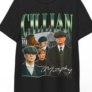 May include: Black t-shirt featuring a vintage-style graphic with the name "Gillian" in green and white. The graphic includes images of several men in hats and suits, with the name "Murphy" in cursive.