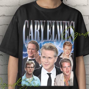 Puede incluir: Camiseta unisex negra con un collage de imágenes de Cary Elwes y el nombre "CARY ELWES" en plata, fuente retro. El diseño tiene una estética vintage, sobre un fondo de pared de ladrillo.