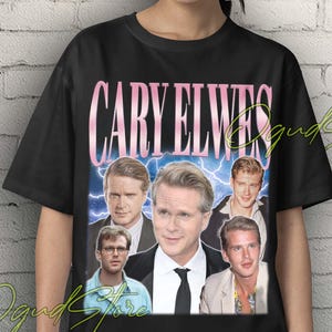 Puede incluir: Camiseta unisex negra con un diseño retro de Cary Elwes. El gráfico incluye el nombre "CARY ELWES" en rosa y varias imágenes del actor. Las palabras "Unisex T-Shirt" están en amarillo en la parte superior de la camiseta.
