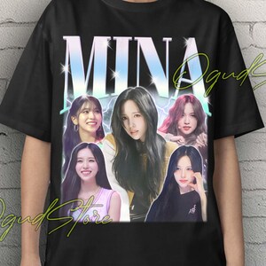 May include: Black Unisex T-shirt featuring the name "MINA" in a gradient font, with images of several women. The shirt has the text "Unisex T-Shirt" in yellow at the top. The shirt is worn by a person.