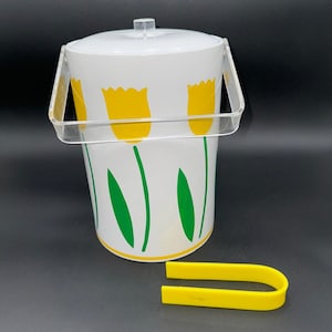 May include: White ice bucket with a clear handle and lid, decorated with yellow tulip flowers and green stems. Includes a pair of yellow plastic tongs. A vintage-style barware set.