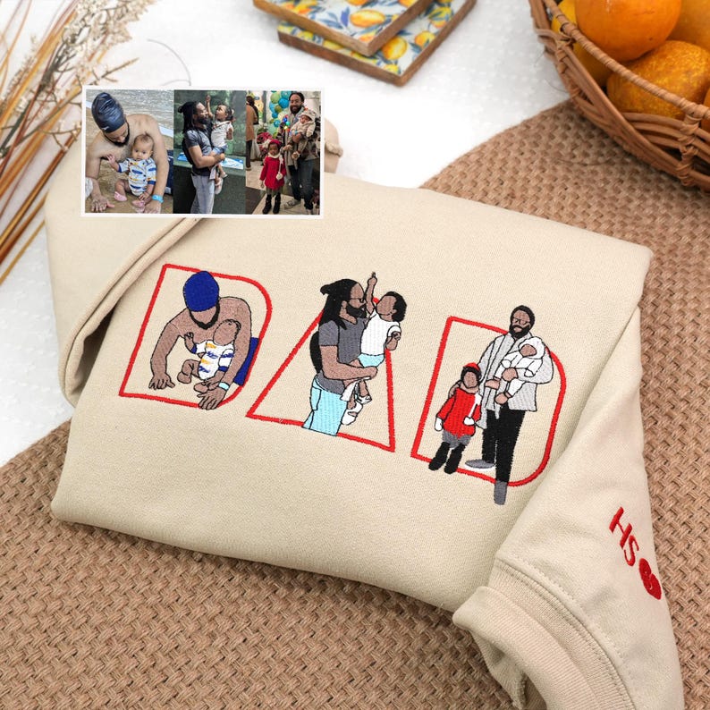 Sand embroidered sweatshirt with “DAD” letters personalized with custom illustrations of dad and children from real family photos. Sleeve detail with initials and heart. Perfect Father’s Day or Christmas gift, sentimental custom sweatshirt for dads.