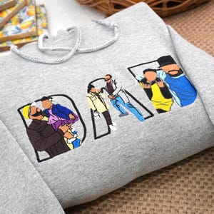 Sport Gray embroidered hoodie featuring “DAD” letters filled with colorful illustrations of dad with children, based on customer family photo. Sleeve personalized with kids’ names. Unique Father’s Day gift, birthday gift, or custom keepsake sweatshirt for dads.