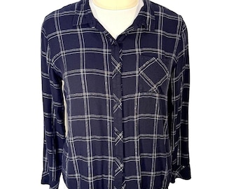 May include: A long-sleeve button-down shirt in navy blue featuring a white grid plaid pattern. The shirt includes a standard collar, a single chest pocket on the left side, and a full-length front button closure with matching navy blue buttons.