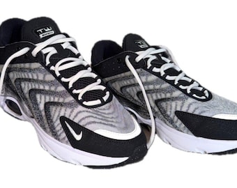 May include: A pair of Nike Air Max TW sneakers featuring a grey and black wavy patterned mesh upper, black synthetic overlays, white laces, and a white midsole. The tongue displays a black patch with the white text TW AIR MAX.