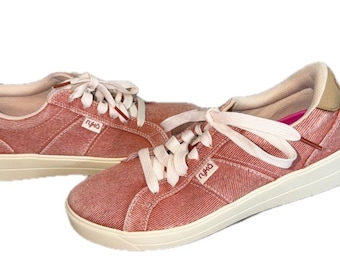 May include: A pair of low-top sneakers in a textured, dusty rose fabric with cream-colored laces and soles. The side of each shoe features the brand name Ryka in small white lettering. The interior lining is beige with a bright pink insole.