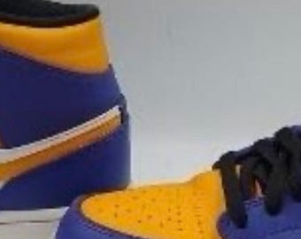 May include: A high-top sneaker featuring a vibrant purple and yellow leather upper with a white side swoosh, black laces, and a white midsole. The design includes a perforated yellow toe box and a solid purple heel panel with a yellow collar.