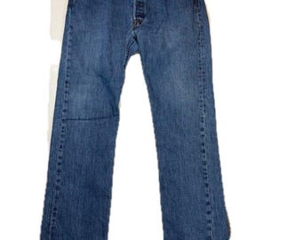 May include: A pair of medium-wash blue denim jeans featuring a classic five-pocket design, a button-fly closure, a waistband with belt loops, and copper-toned rivets at the pocket corners. The jeans have a straight-leg cut and visible stitching.