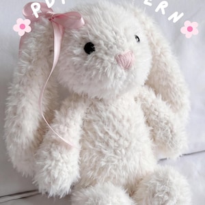 May include: A plush white bunny toy with long ears, black eyes, and a pink stitched nose. A light pink satin ribbon is tied in a bow on one ear. The text PDF PATTERN is printed at the top, flanked by two small pink flower icons on each side.