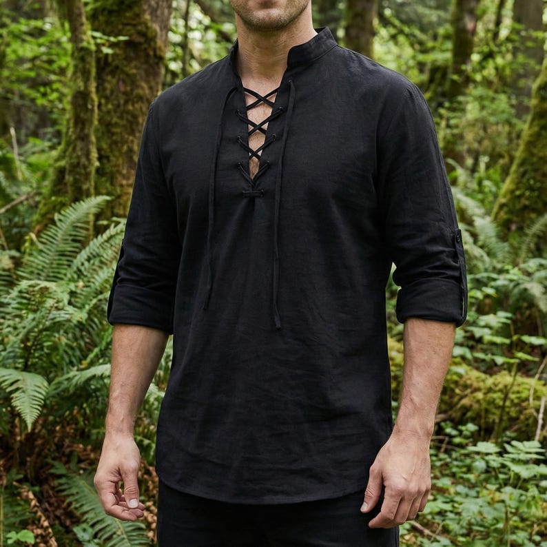 Pode incluir: Camisa preta de manga comprida com gola mandarim e atacadores na frente. As mangas est&atilde;o enroladas at&eacute; aos cotovelos. A camisa &eacute; feita de um tecido macio e respir&aacute;vel. O fundo &eacute; uma exuberante floresta verde.