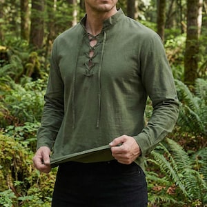 Pode incluir: Camisa de manga comprida verde-oliva com gola alta e decote com atacadores. A camisa tem mangas compridas e &eacute; feita de um tecido leve. A camisa &eacute; de estilo casual.