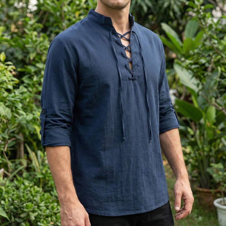 Pode incluir: Uma camisa azul marinho de manga comprida com gola mandarim e decote com atacadores. A camisa tem punhos abotoados e &eacute; feita de um tecido leve. A camisa &eacute; de estilo casual.