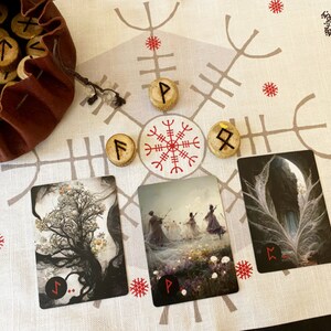 Puede incluir: Un pa&ntilde;o blanco con un patr&oacute;n rojo y gris. Tres cartas con im&aacute;genes de un &aacute;rbol, un grupo de personas bailando y una pluma. Cuatro runas de madera con s&iacute;mbolos est&aacute;n colocadas en el pa&ntilde;o.