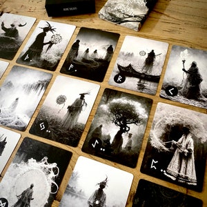 May include: A set of 10 black and white tarot cards with intricate illustrations and runes. The cards feature a variety of mystical and symbolic imagery, including trees, figures, and abstract patterns.