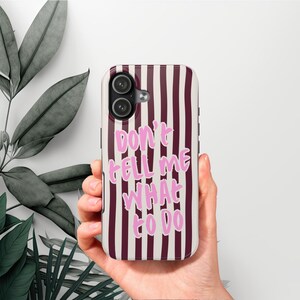 Può includere: Custodia per smartphone con motivo a righe verticali bordeaux e bianche. La custodia presenta il testo "DON'T TELL ME WHAT TO DO" in rosa. La custodia ha un ritaglio per una fotocamera a doppia lente.