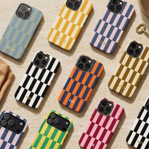 Puede incluir: Una colección de fundas para smartphone con un patrón de cuadros en varias combinaciones de colores, incluyendo azul y verde, amarillo y blanco, rosa y azul, negro y blanco, naranja y azul, marrón y beige, y rojo y rosa, cada una con iniciales.