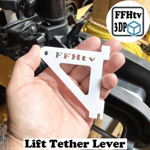 May include: A white, triangular Lift Tether Lever with the text "FFHtv" cut out. The lever has a small hole at the top and a notch at the bottom. The image also includes a logo with the text "FFHtv 3DP".