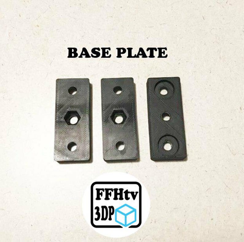 May include: Three rectangular black base plates with pre-drilled holes. Two plates feature a central hexagonal cutout, while the third has a circular center hole. The text BASE PLATE is printed above, and a logo with FFHtv 3DP is below.