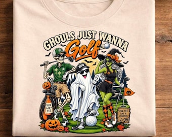 May include: A beige t-shirt featuring a graphic of a skeleton, a ghost, and a witch playing golf. The text reads GHOULS JUST WANNA GOLF. The skeleton wears a green polo and cap, the ghost wears a black cap, and the witch wears a black hat and dress.