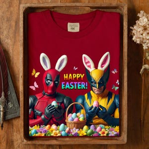 May include: A maroon sweatshirt with a colorful "Happy Easter!" graphic. The graphic features Deadpool and Wolverine wearing bunny ears and holding Easter eggs, with a basket of eggs and butterflies.