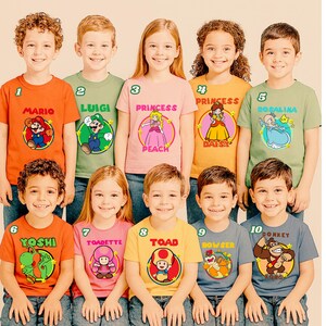 May include: A collection of ten short-sleeved t-shirts in various colors, each featuring a circular graphic of a Super Mario character. The shirts display the names Mario, Luigi, Princess Peach, Daisy, Rosalina, Yoshi, Toadette, Toad, Bowser, and Donkey Kong.