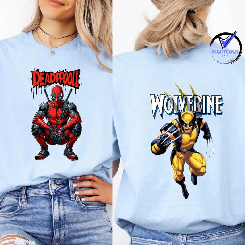 May include: Light blue t-shirts featuring comic book characters. One shirt displays Deadpool in a crouching pose with the text "DEADPOOL". The other shirt shows Wolverine with the text "WOLVERINE". Both shirts have a graphic print.