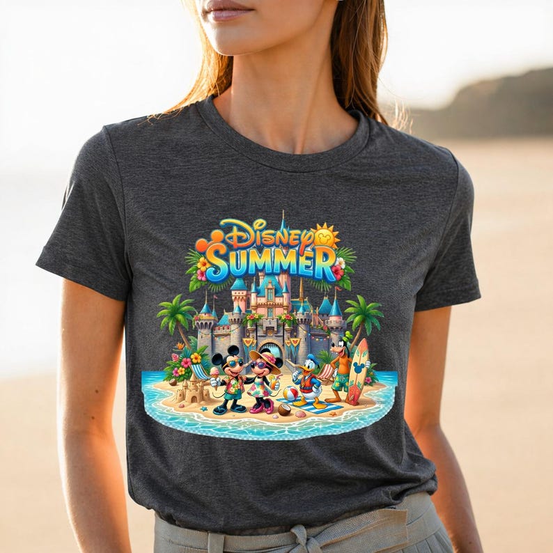 May include: A dark gray t-shirt featuring a colorful graphic of Disney characters Mickey Mouse, Minnie Mouse, Donald Duck, and Goofy on a beach in front of a castle. The text Disney SUMMER is printed in blue and yellow above the characters.