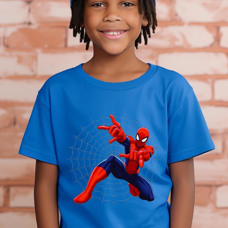 Puede incluir: Camiseta azul con un dise&ntilde;o de Spider-Man. La ilustraci&oacute;n muestra a Spider-Man en una pose din&aacute;mica con una telara&ntilde;a. El superh&eacute;roe est&aacute; en su traje rojo y azul, con los brazos extendidos.