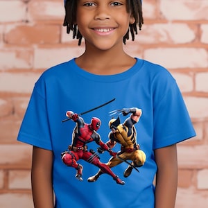 May include: A blue t-shirt featuring a graphic of Deadpool and Wolverine in action. Deadpool is in a red and black suit, and Wolverine is in a yellow and black suit. The characters are posed in a dynamic fighting stance.