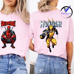 May include: Pink t-shirts featuring comic book characters. One shirt displays "DEADPOOL" with Deadpool in a crouching pose. The other shirt shows "WOLVERINE" with Wolverine in a running pose. Both shirts are paired with blue jeans.