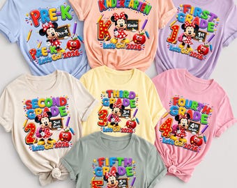 May include: A collection of seven short-sleeved t-shirts in various pastel colors, each featuring a graphic of Minnie Mouse, a red apple, pencils, and text indicating school grade levels from Pre-K to Fifth Grade with the year 2026.