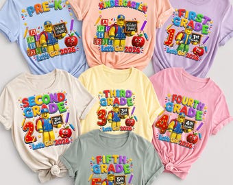 May include: A collection of seven short-sleeved t-shirts in various pastel colors, each featuring a cartoon character wearing a backpack and holding a chalkboard. The shirts display school grade levels from Pre-K to Fifth Grade and the text Let's Go 2026.