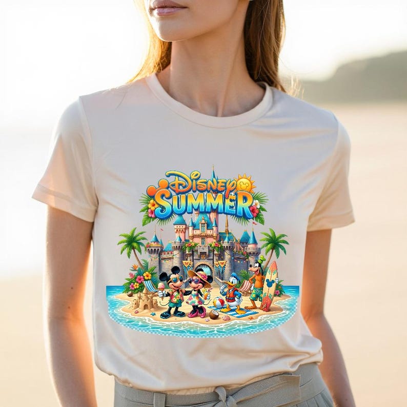 May include: A cream-colored short-sleeve t-shirt featuring a colorful graphic print of Disney characters including Mickey Mouse, Minnie Mouse, Donald Duck, and Goofy at a beach with a castle, palm trees, and the text Disney Summer.