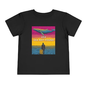 Könnte beinhalten: Schwarzes T-Shirt für Kleinkinder mit einem Grafikdesign. Das Design zeigt einen Wal, eine Person mit einem Koffer und den Text "404 SEA NOT FOUND". Der Hintergrund hat rosa, gelbe und blaue Farbtöne.