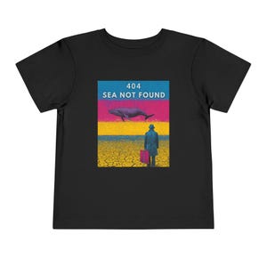 以下が含まれることがあります： 「404 SEA NOT FOUND」の文字が入ったグラフィックが特徴の黒い幼児用Tシャツ。クジラ、スーツケースを持った人物、ひび割れた地面のデザインが、カラフルな空を背景に描かれています。
