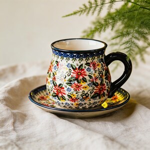 Botanical tea mug with red blooms, green leaves, and dark blue decorative rim