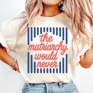 May include: An ivory short-sleeved t-shirt featuring a graphic design with vertical navy blue stripes and the text "the matriarchy would never" written in a coral-colored cursive font centered on the front of the garment.