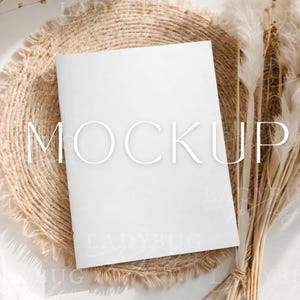 May include: A white ceramic mug with a black handle and the text "But First, Coffee" in a bold, black font. The mug is set against a blurred background, suggesting a cozy setting.