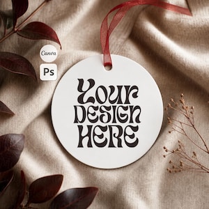 May include: A circular white ornament featuring the black text YOUR DESIGN HERE in a stylized font. The ornament is suspended by a thin red ribbon, providing a clean surface for customization. The design is centered on the smooth white disc.