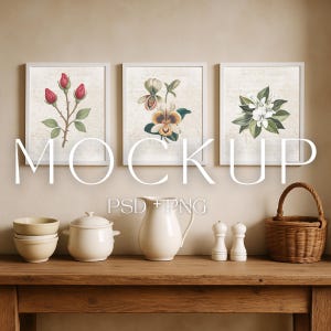 May include: Three framed botanical prints with white frames and floral illustrations. A wooden table displays a stack of bowls, a lidded pot, a pitcher, salt and pepper shakers, and a woven basket. The word "MOCKUP" is displayed.