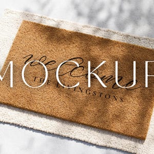 以下が含まれることがあります： 「welcome」の文字が筆記体で書かれ、「The Livingstons」が下に書かれた、長方形のドアマット。明るい茶色で、白くふわふわのラグの上に置かれています。テキストは黒色です。